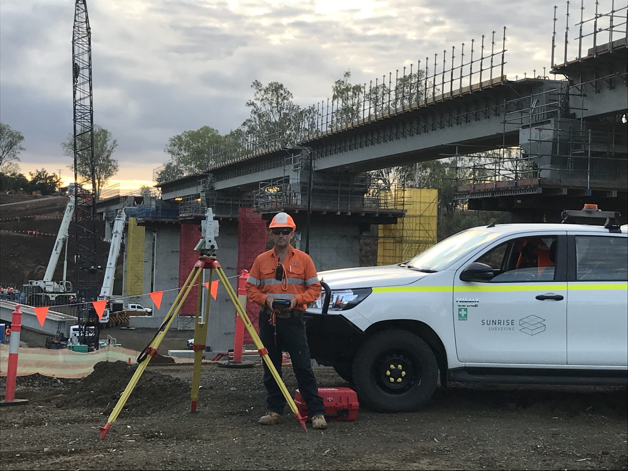male surveyor standing next to vehicle on a construction site